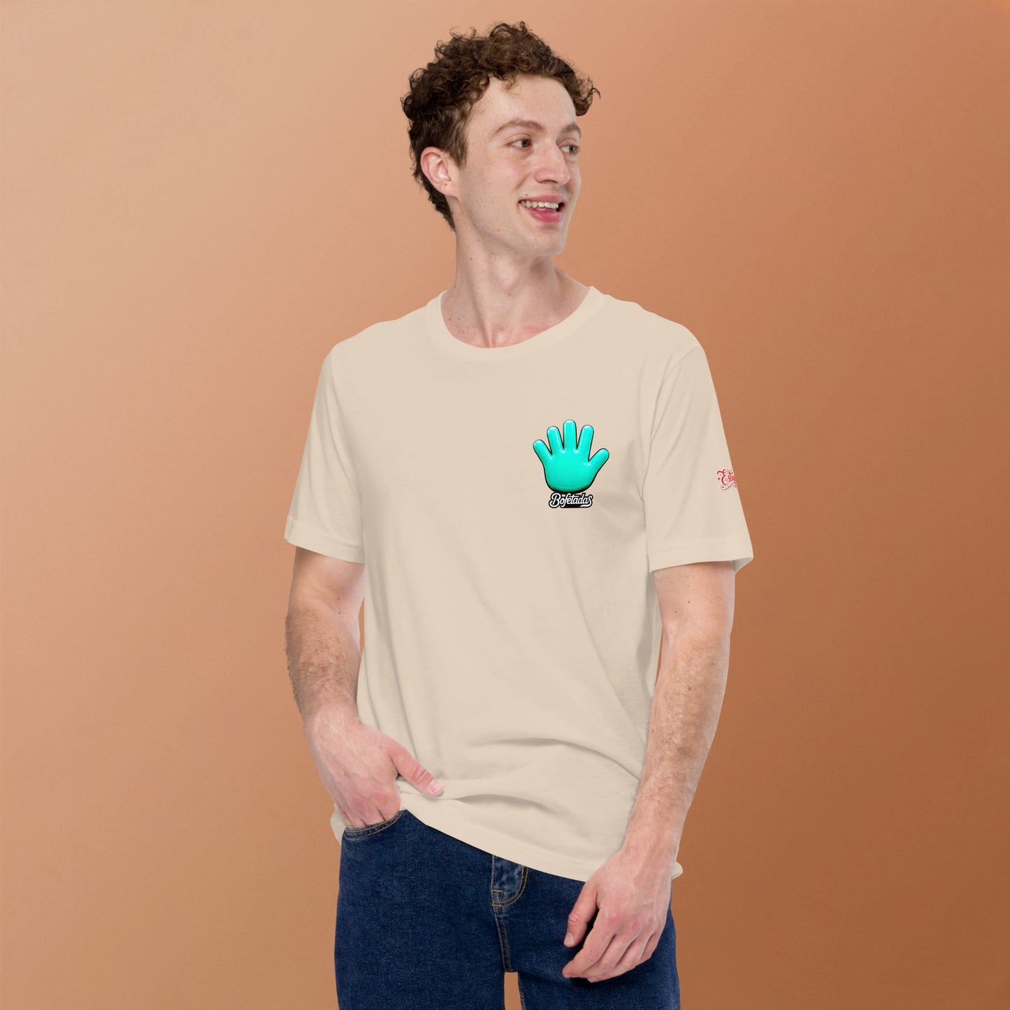 Vista frontal de una camiseta beige de manga corta de la marca Bofetadas, con la impresión del logotipo de Bofetadas con la mano azul en el pecho. La luce un modelo sonriente.