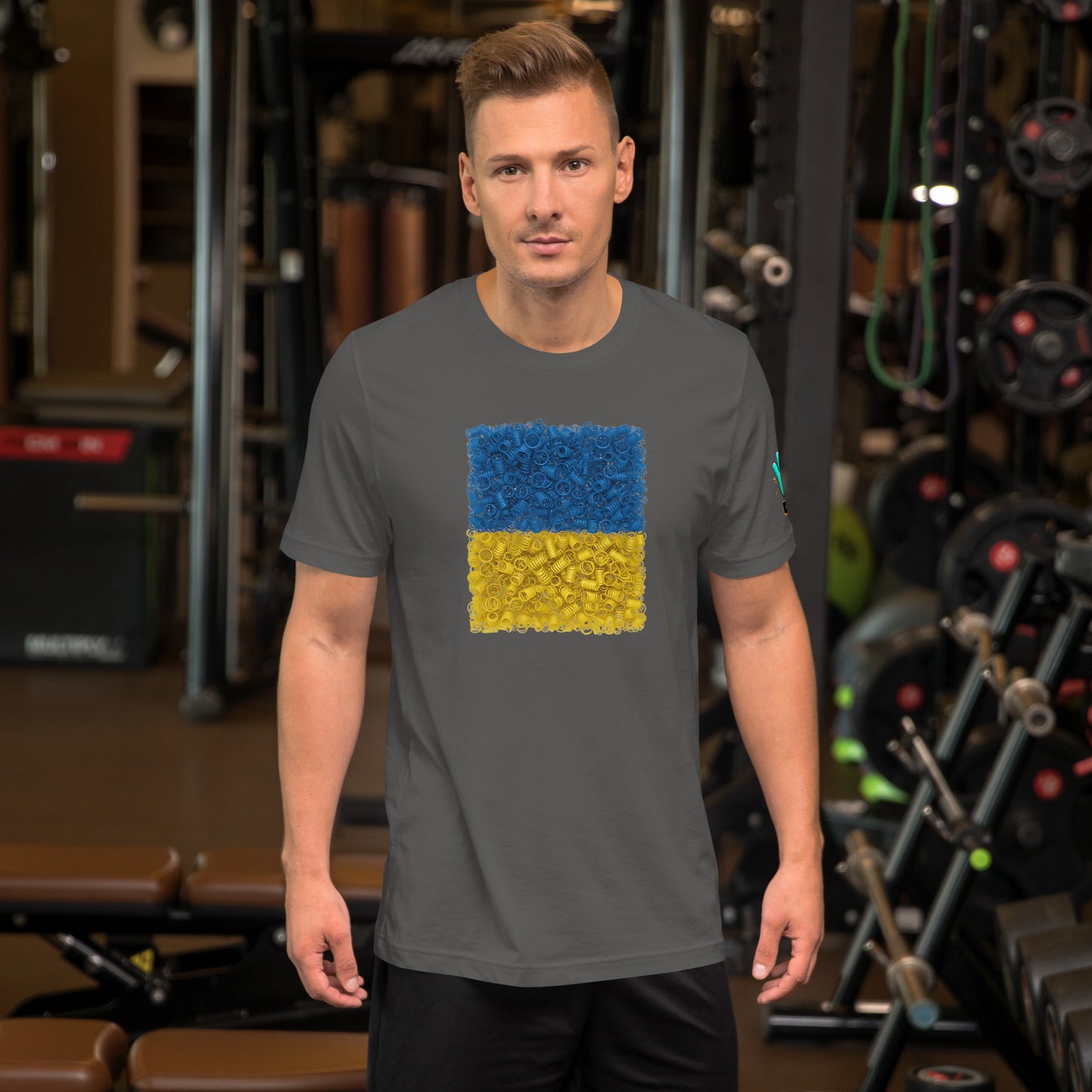 Vista frontal de una camiseta gris de manga corta de la colección Causas Sociales, con una impresión de la bandera de Ucrania formada por muelles que simbolizan la resistencia. La camiseta la lleva un modelo.