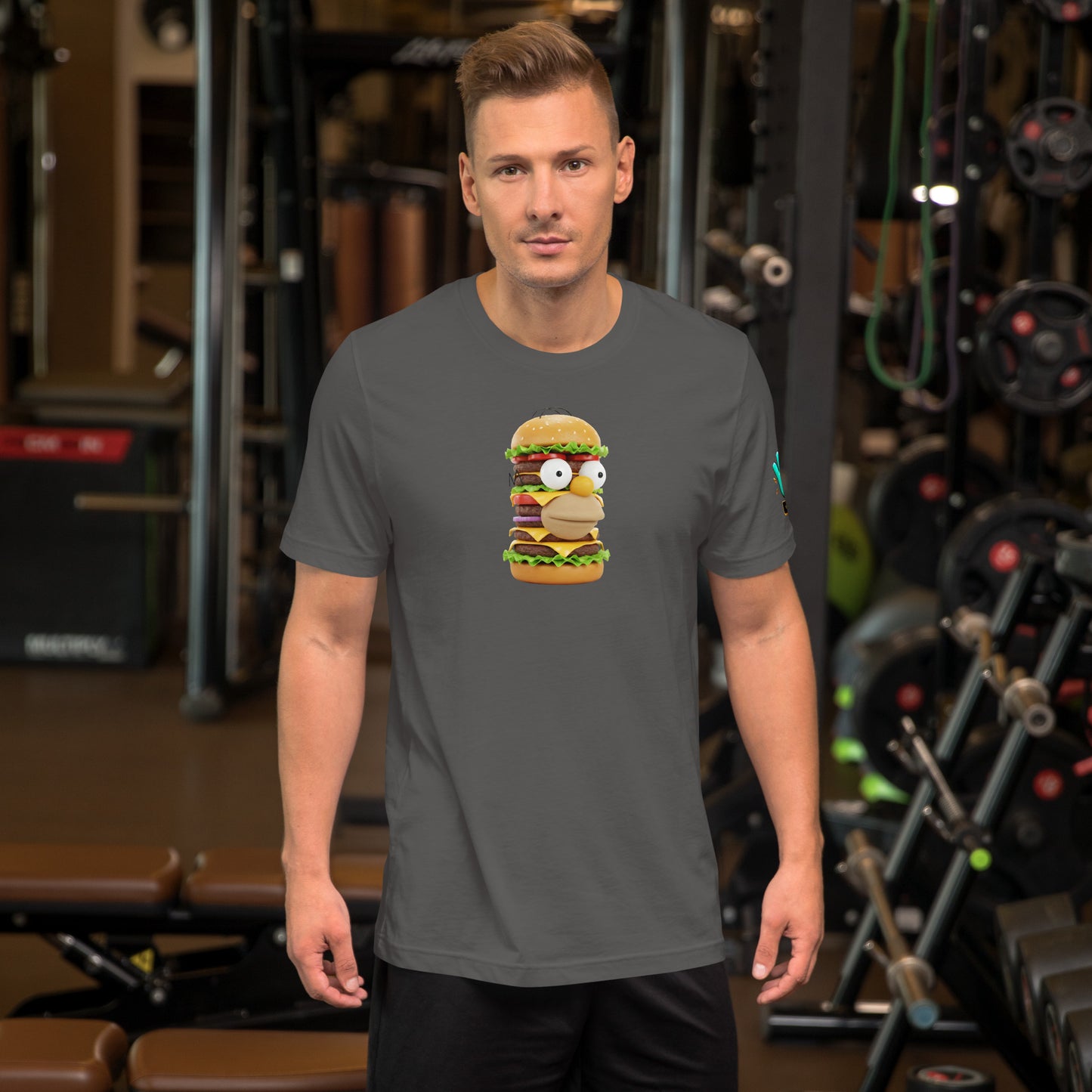 Modelo en gimnasio luciendo camiseta gris de manga corta marca Bofetadas, colección 'Pop', con Homer Simpson en hamburguesa de plástico de varios pisos.