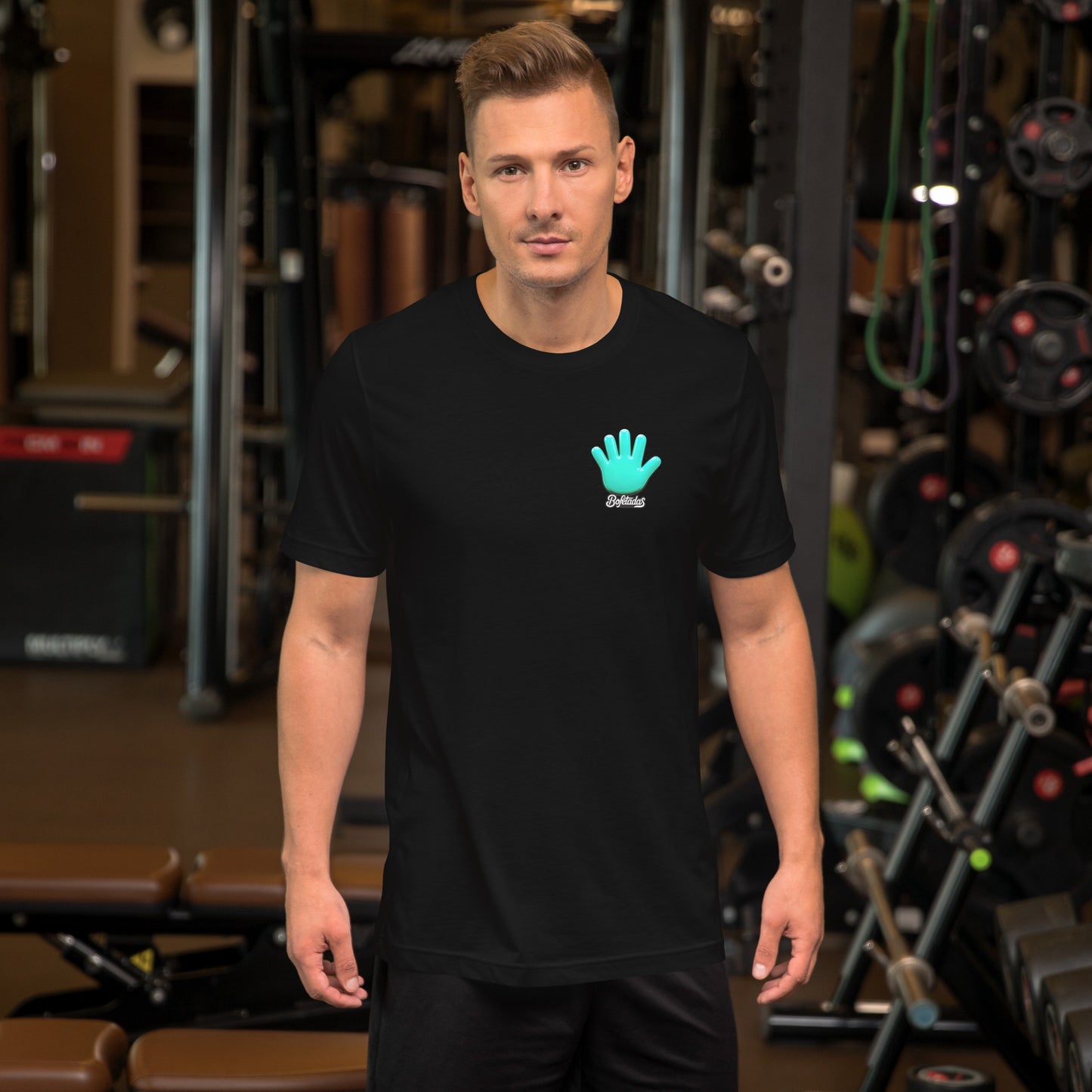 Un modelo en un gimnasio luce una camiseta negra de manga corta marca Bofetadas, colección 'Gótica', con el logo de la mano azul en el pecho.