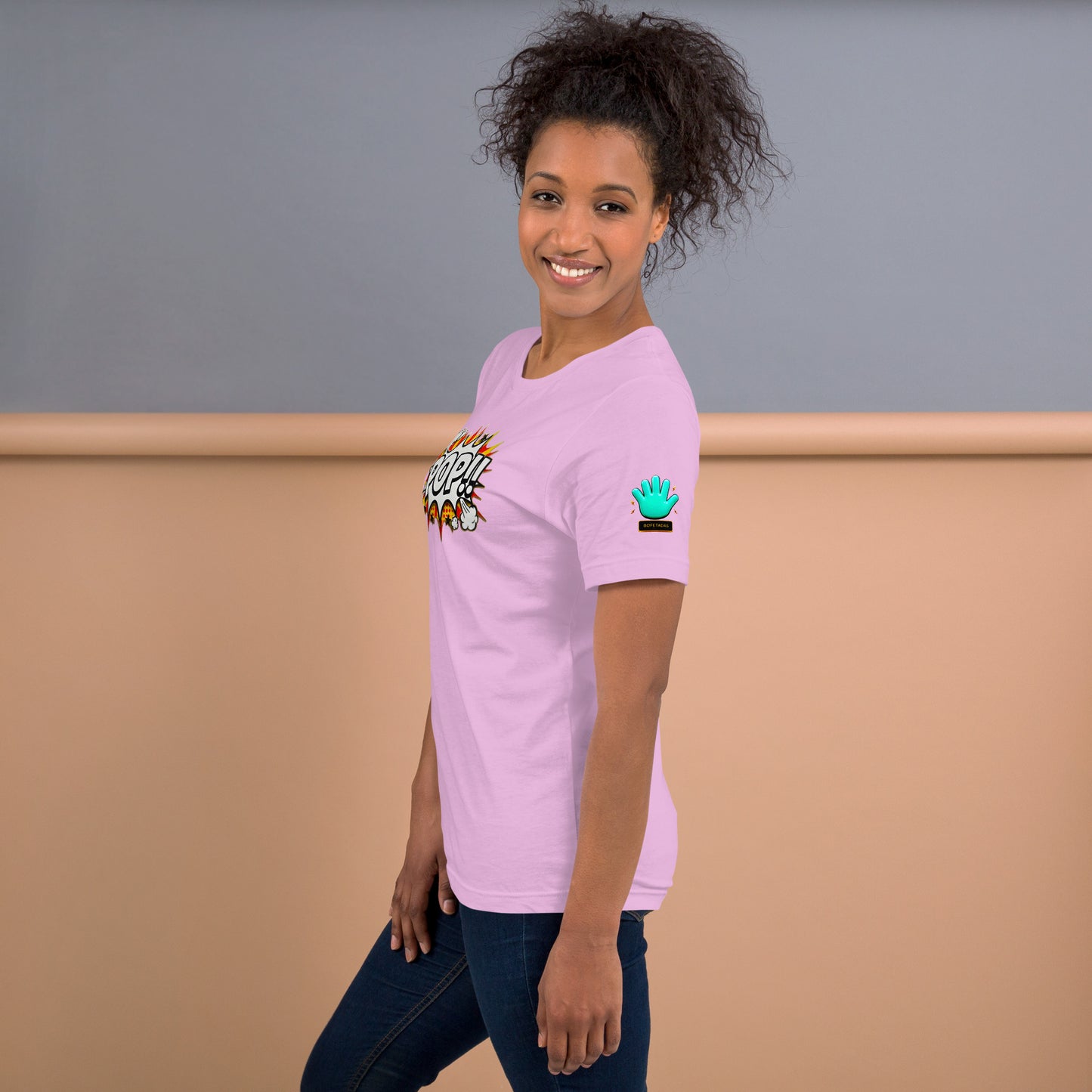 Una modelo sonriente mostrando la vista lateral de camiseta rosa de manga corta, marca Bofetadas, colección 'Pop', con el logotipo de una mano azul en la manga.