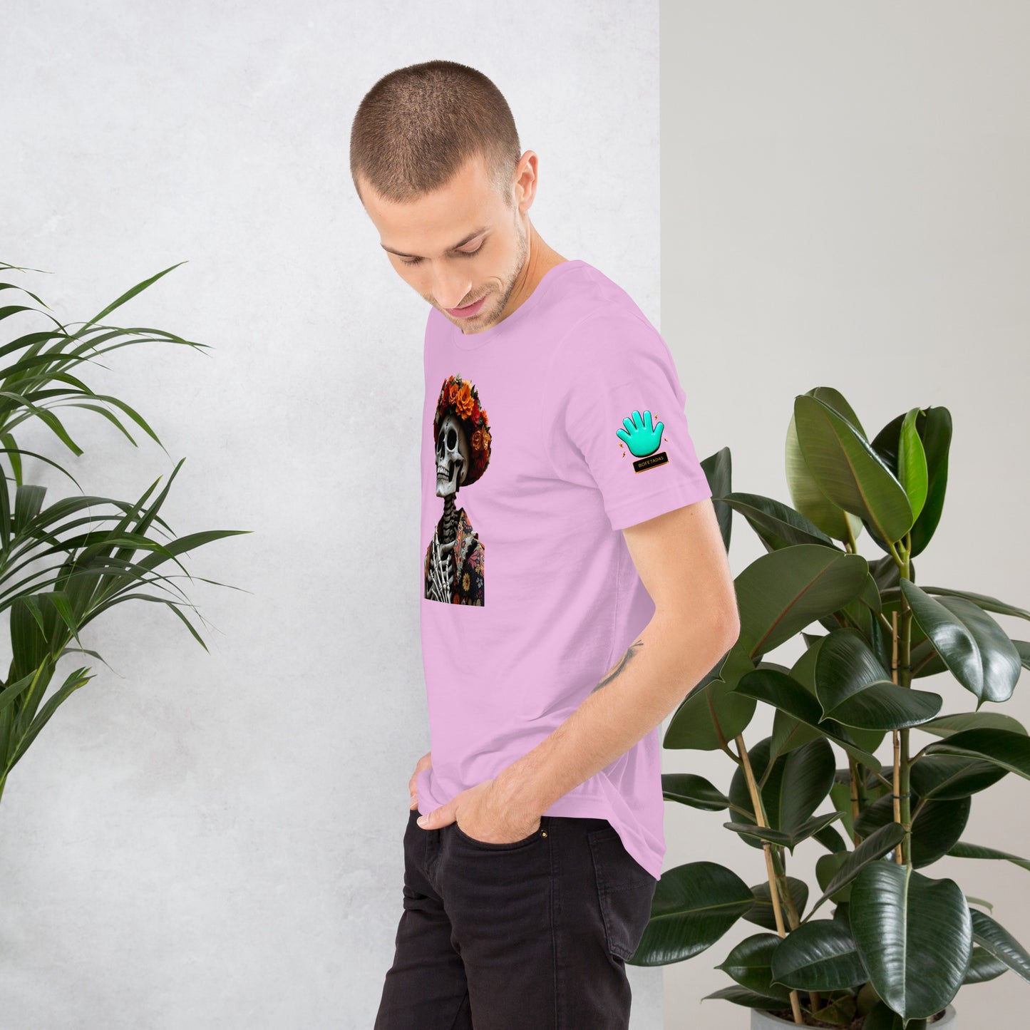 Modelo tatuado mostrando la vista lateral de camiseta rosa de manga corta, marca Bofetadas, colección 'Calaveras', con el logotipo de una mano azul en la manga.
