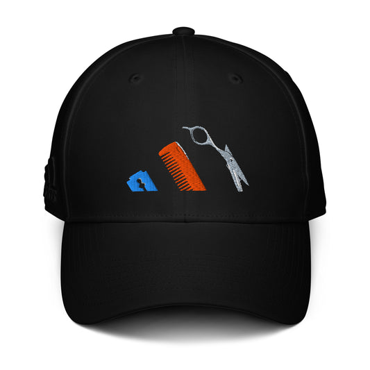 Gorra negra de la colección Adidas Bofetadas. Bordado frontal con las tres bandas del logotipo de Adidas representadas por unas tijeras, un peine y una cuchilla de afeitar, dedicadas al oficio de peluquero.