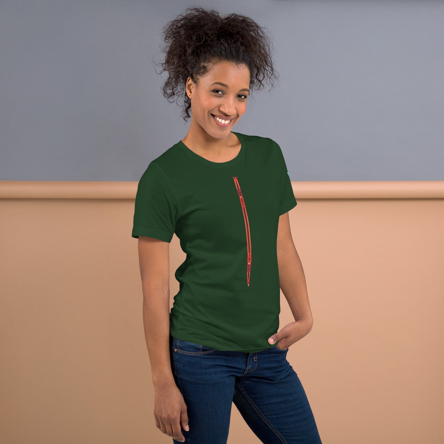 Una modelo nos muestra la camiseta verde de la colección "Mirada" con la impresión en la parte delantera de una ilustración lineal que parece un lápiz o pluma naranja.