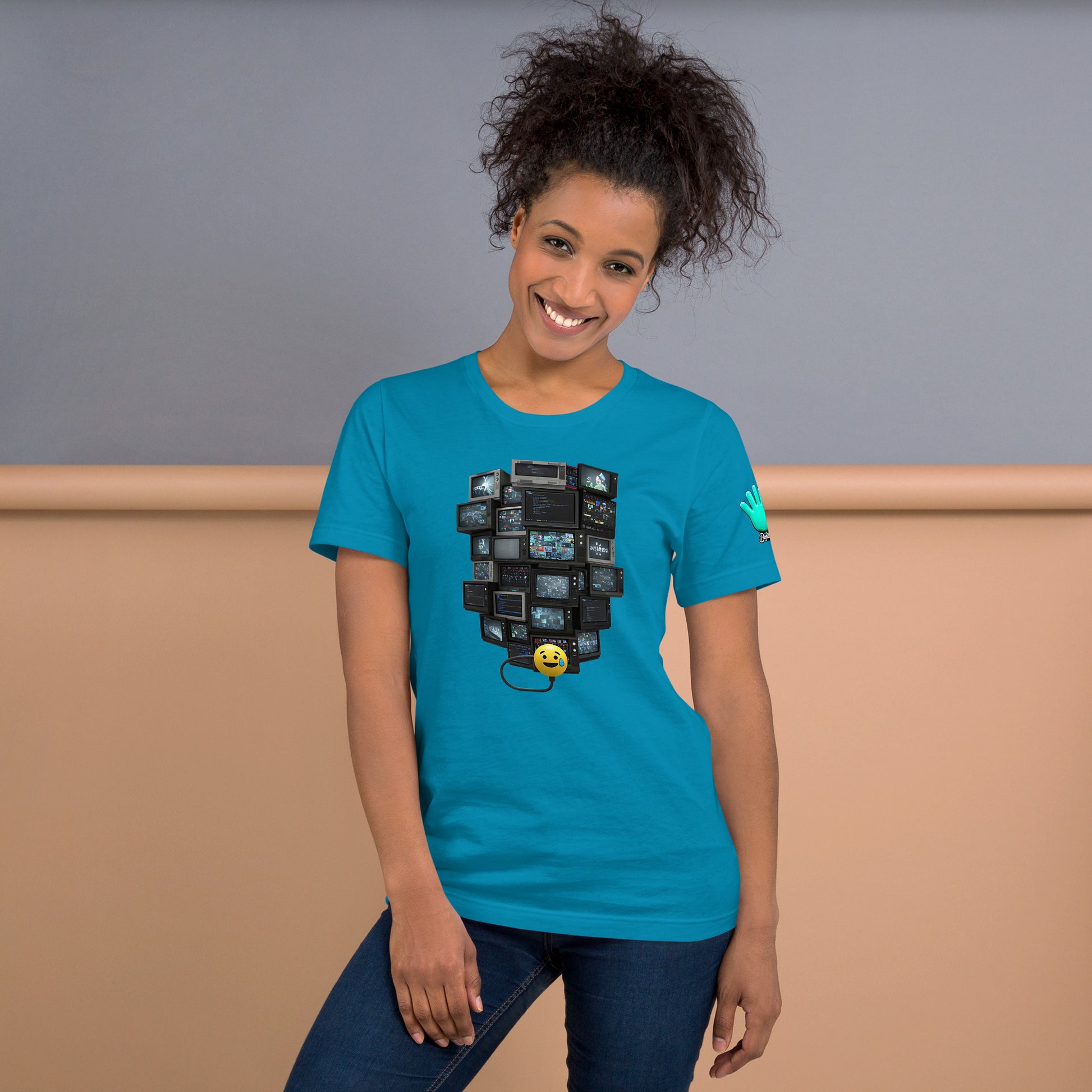 Una modelo sonriente con pelo recogido y jeans luciendo camiseta azul de manga corta marca Bofetadas, colección 'Emojis', vista frontal, con emoji sudando conectado a TVs apiladas.