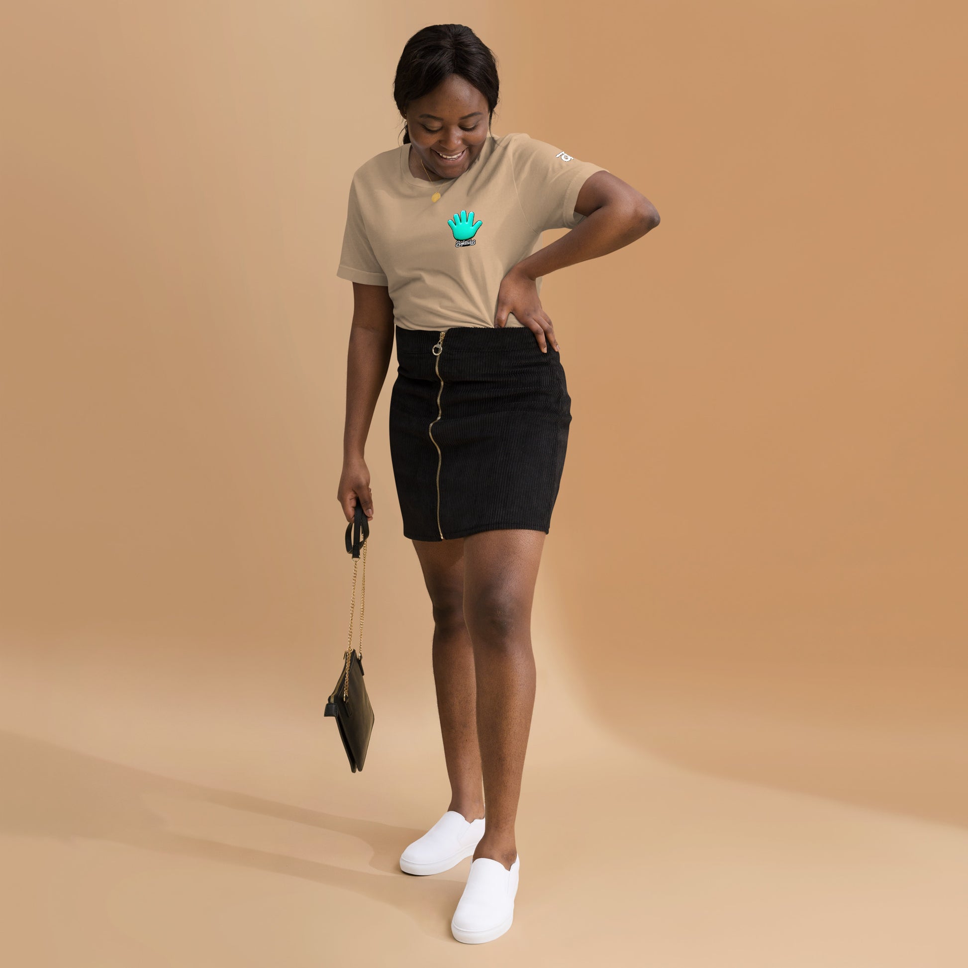 Una modelo con falda y bolso negros mostrando la vista delantera de una camiseta beige de manga corta, marca Bofetadas, colección 'Irreverentes', con la impresión del logo de Bofetadas en el pecho.