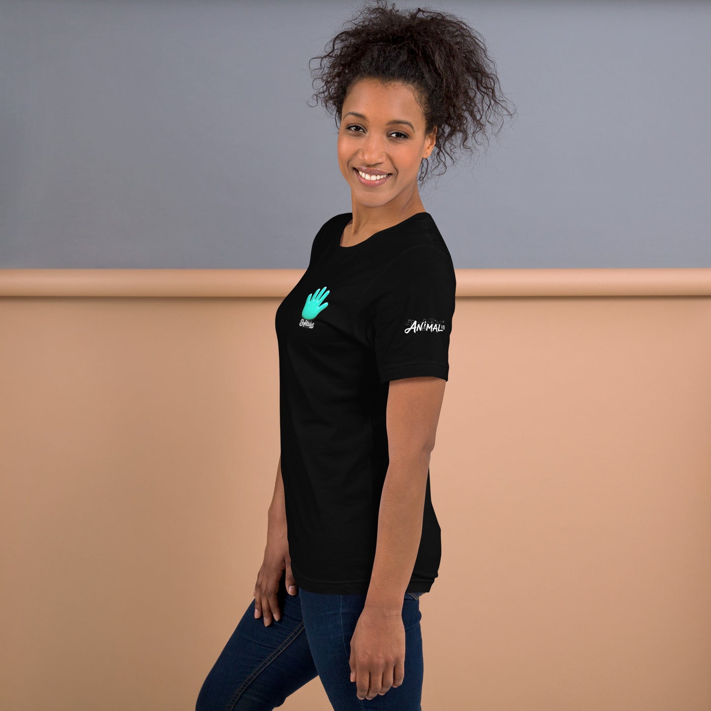 Vista lateral de la camiseta negra que luce una modelo ladeada y sonriente con vaqueros de la colección Marca y serie Sports de Bofetadas. En la manga izquierda tiene impreso el texto decorado "ANIMAL" y en el pecho esta impreso el logotipo de Bofetadas y el nombre Bofetadas.