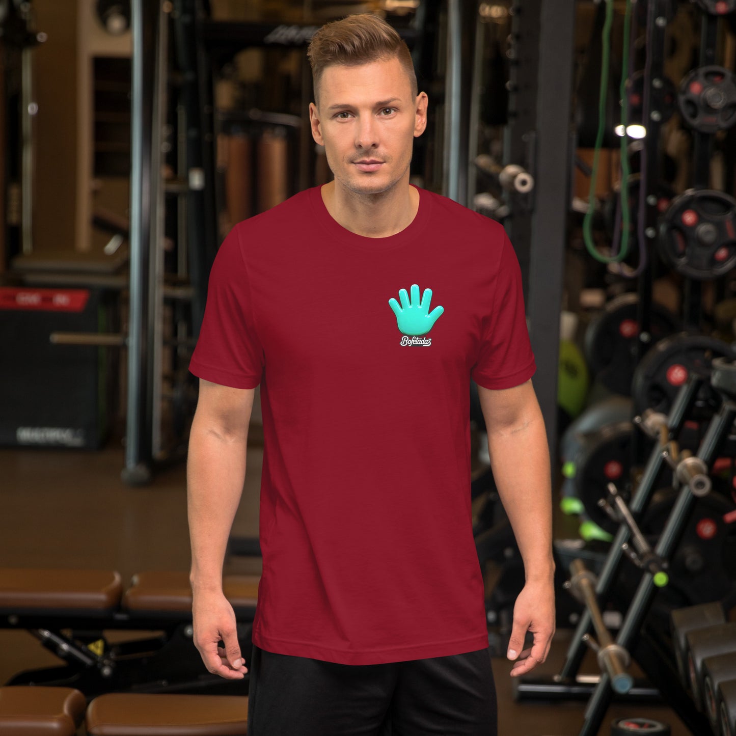 Modelo en un gimnasio luciendo la camiseta granate de la colección 'Pop', vista frontal, con el logo de la mano azul y el nombre de la marca 'Bofetadas' en el pecho.