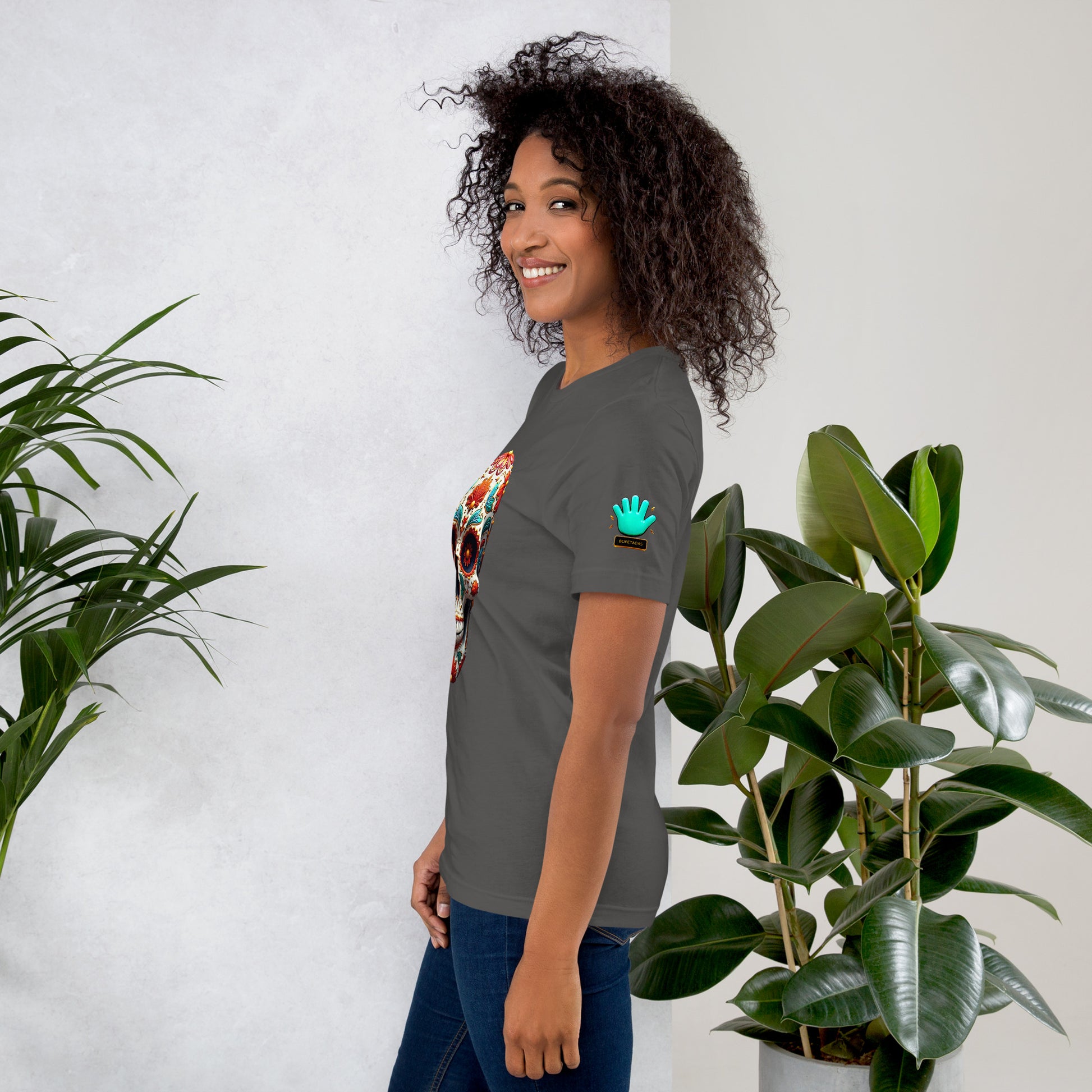 Modelo mostrando la vista lateral de camiseta gris de manga corta, marca Bofetadas, colección 'Calaveras', con el logotipo de una mano azul en la manga.