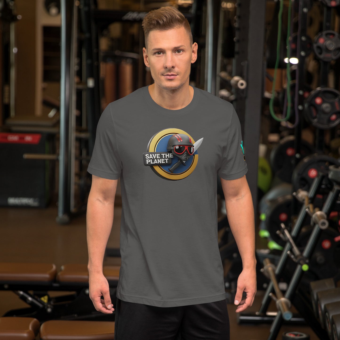 Modelo en gimnasio luciendo camiseta gris de manga corta marca Bofetadas, colección 'Causas Sociales', con escudo 'save the planet', casco y cuchillo.