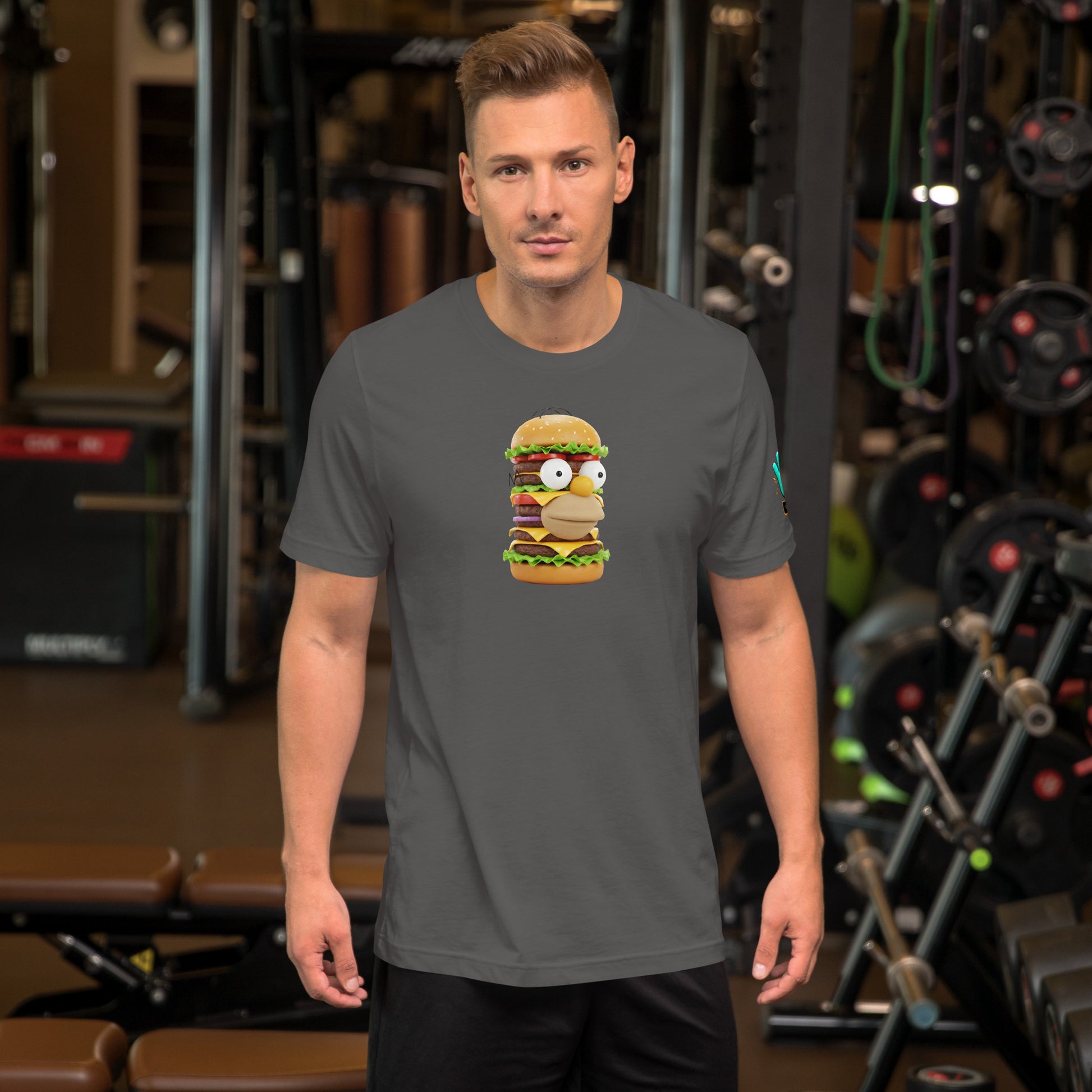 Modelo en gimnasio luciendo camiseta gris de manga corta marca Bofetadas, colección 'Pop', con Homer Simpson en hamburguesa de plástico de varios pisos.