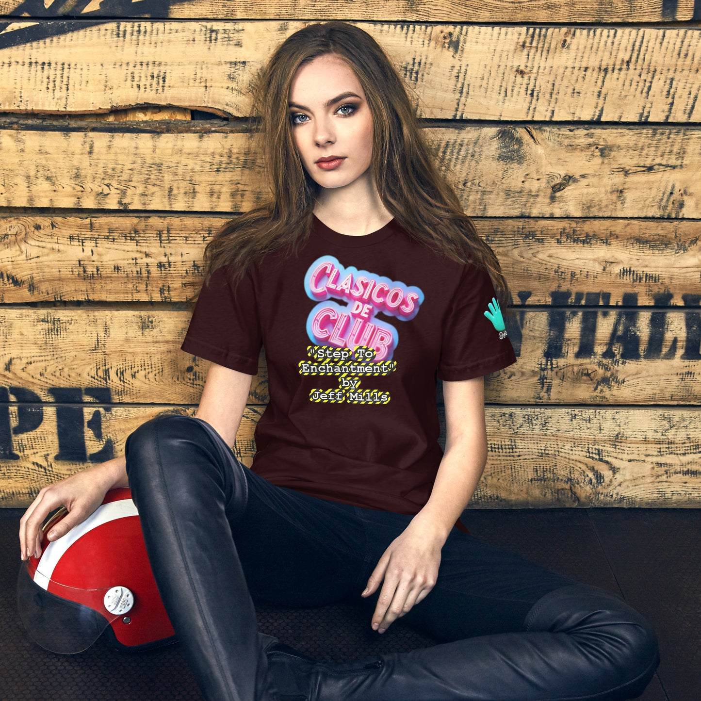 Camiseta marrón de manga corta de la colección Clásicos de Club, dedicada al tema 'Step to Enchantment' de Jeff Miles, un tema de techno Detroit. En la imagen se muestra una modelo sentada con un casco de moto, llevando la camiseta con el diseño de la colección.