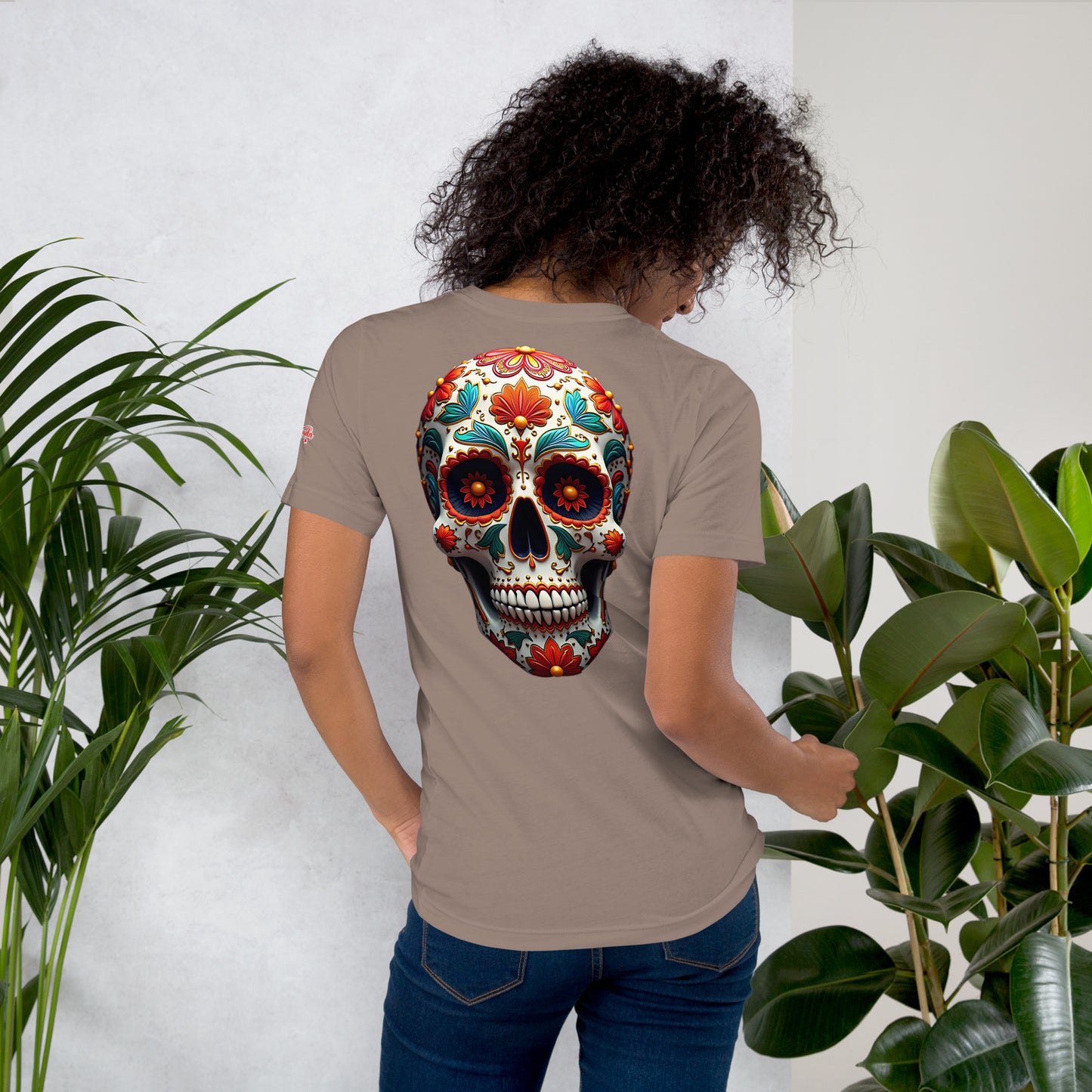 Una modelo con jeans muestra la vista trasera de camiseta gris de manga corta, marca Bofetadas, colección 'Calaveras', con calavera mexicana decorada estilo rococó.