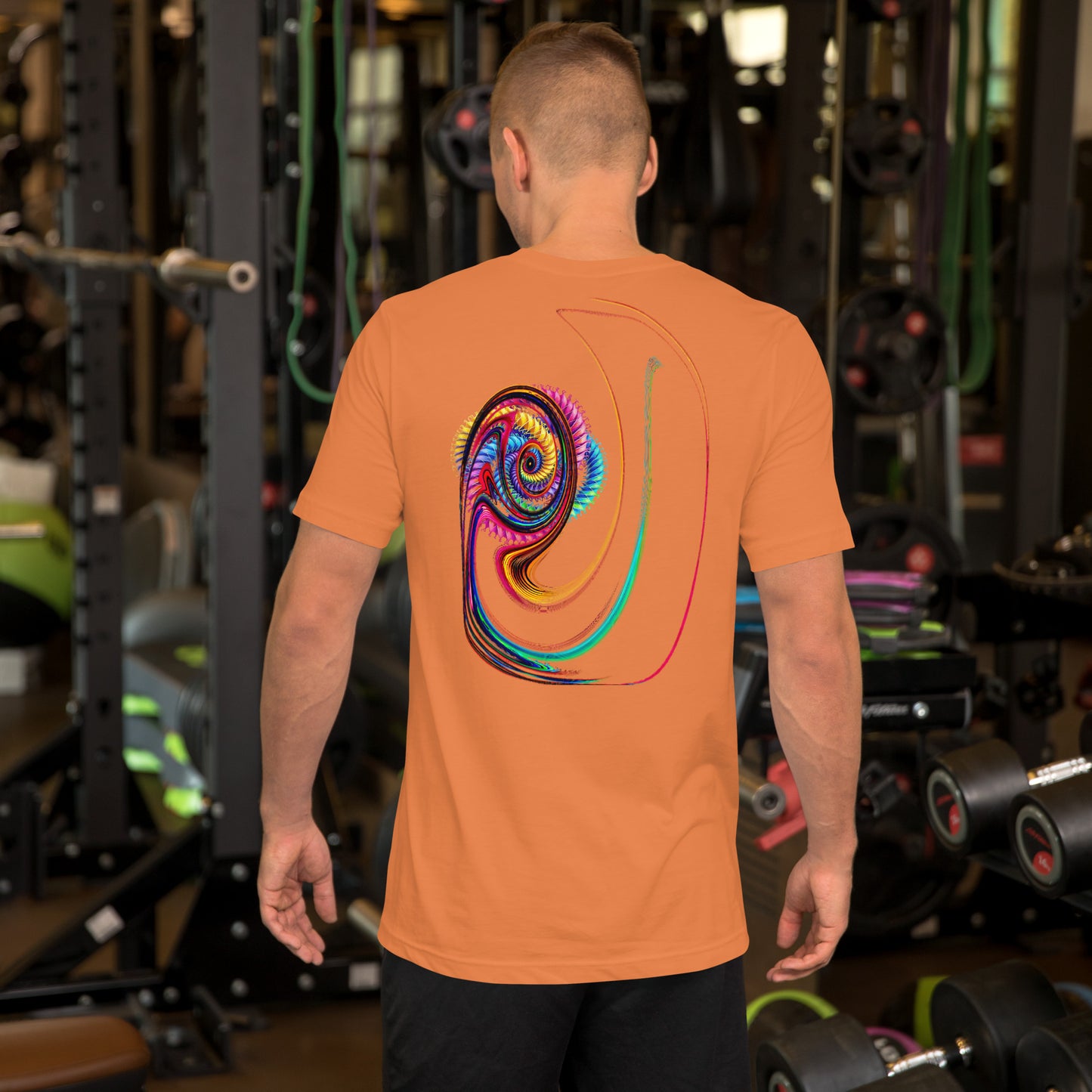 Modelo en gimnasio luce camiseta naranja colección 'Abstracta', vista trasera, con trazos surrealistas que forman un ojo que mira.