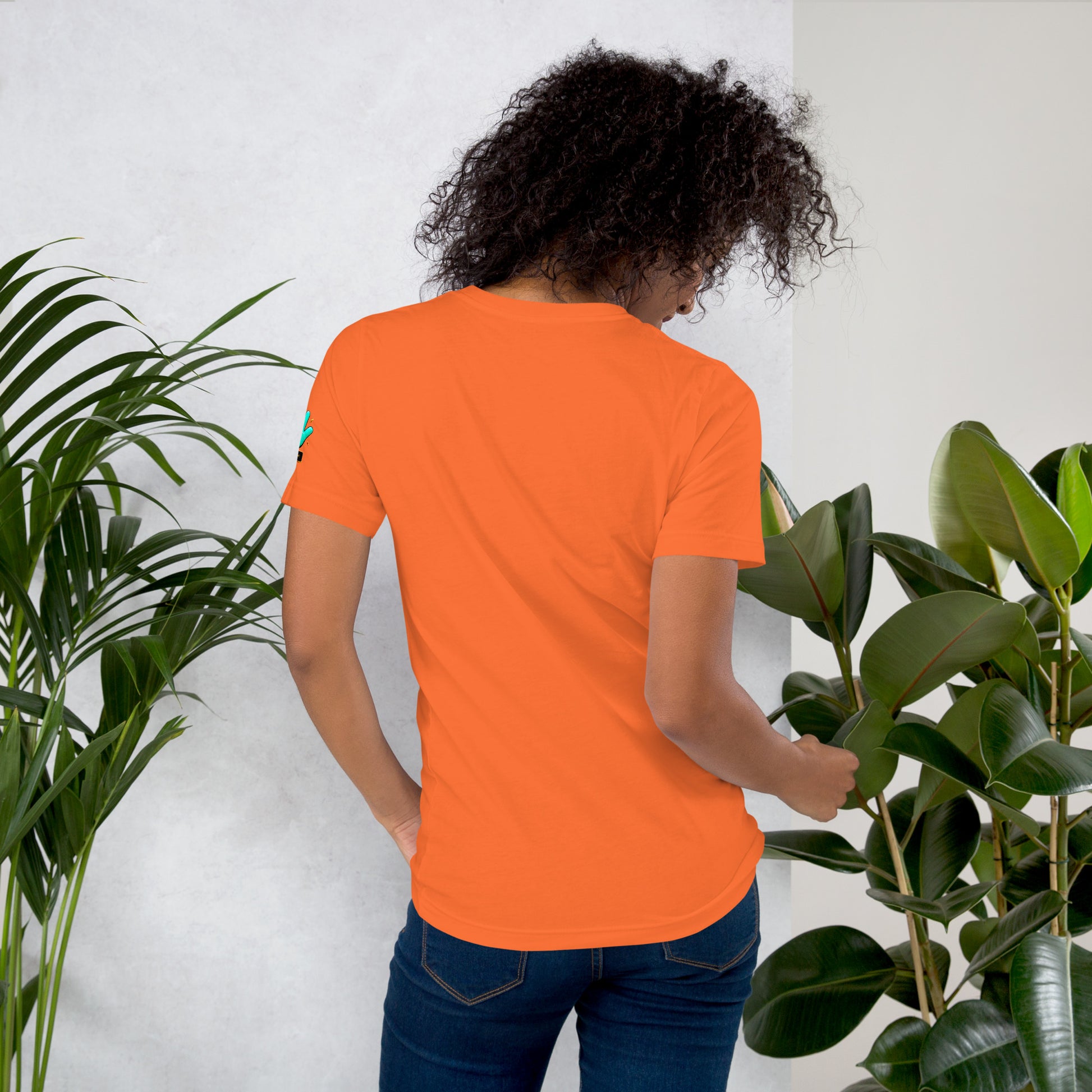 Modelo con jeans mostrando la vista trasera de camiseta naranja de manga corta, marca Bofetadas, colección 'Símbolos', sin impresión.