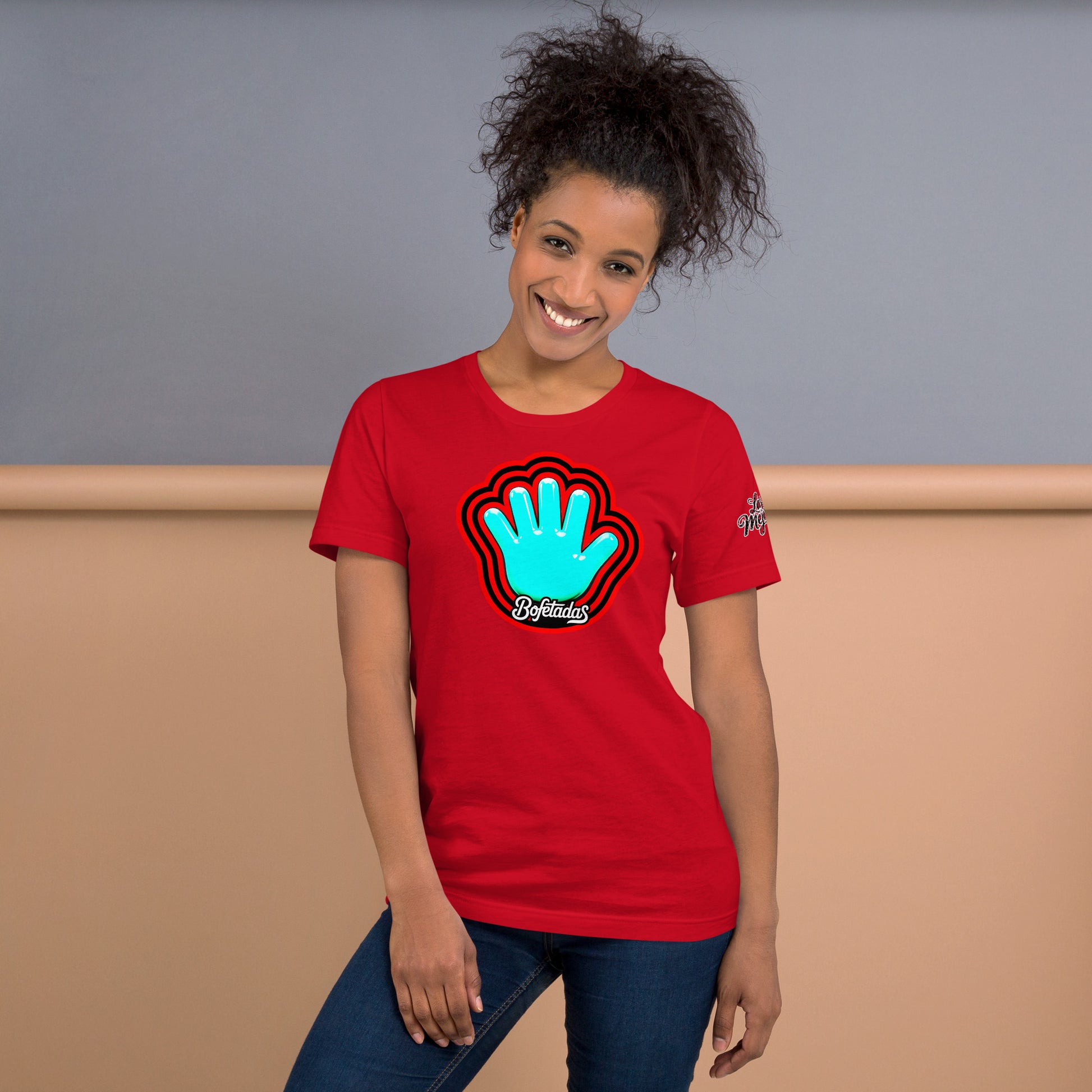 Modelo sonriente con jeans luce camiseta roja colección 'marca', vista frontal, con logo de Bofetadas (mano azul) con aura roja y negra, texto 'bofetadas' con estilo caligráfico inspirado en Pokras Lampas.